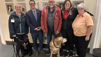 Jennifer Sanderson, Brad Trivers, Russell McCabe, Shannon Noonan and Karen McRae along with two service dogs pose for a photo after first session of debate of the Service Dog Act on Nov 7th 2024.